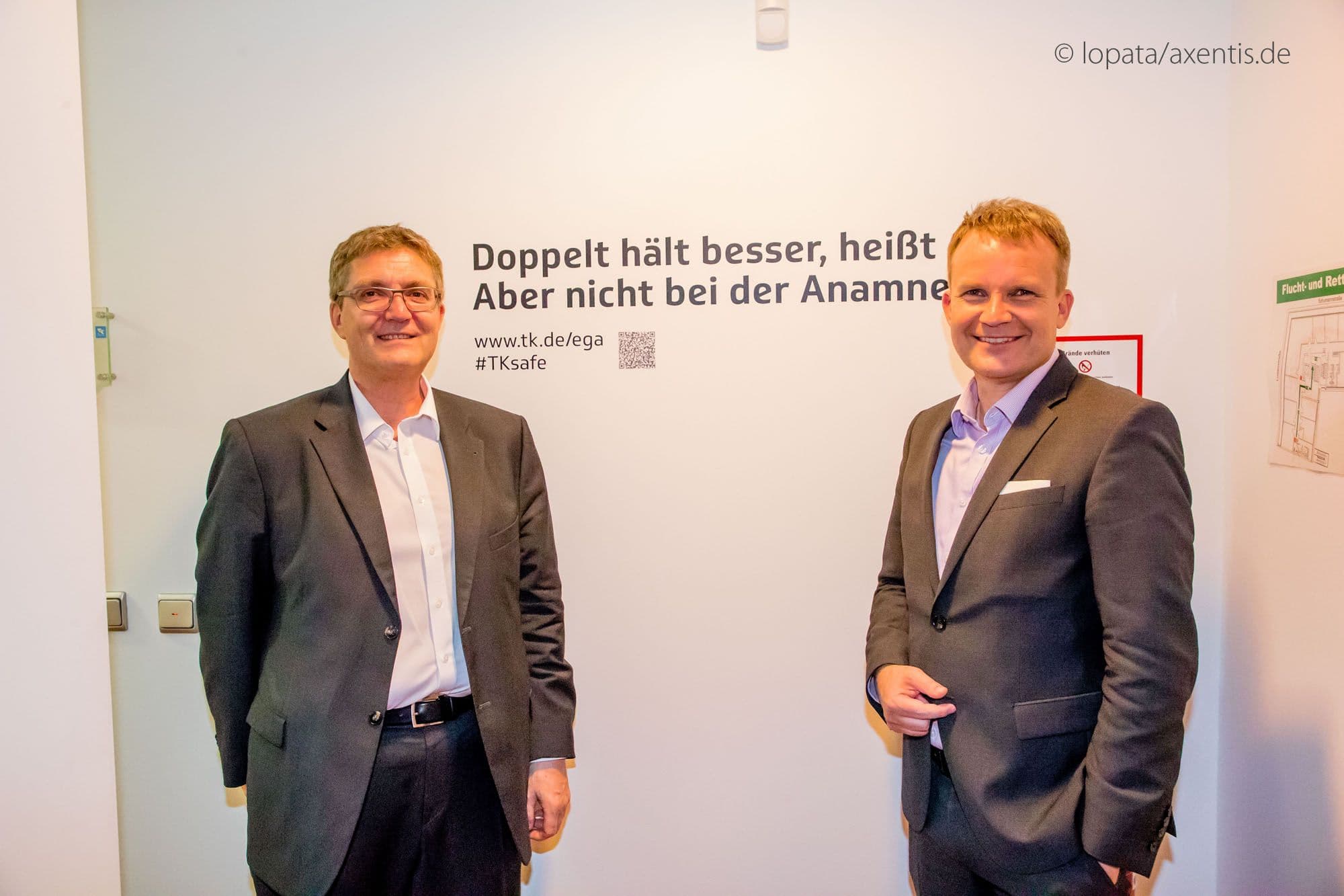 TK-Vorstandsvize Thomas Ballast (l.) und Vorstandsvorsitzender Jens Baas bereit für die Gäste vor einem der Werbesprüche zur elektronischen Gesundheitsakte der TK.