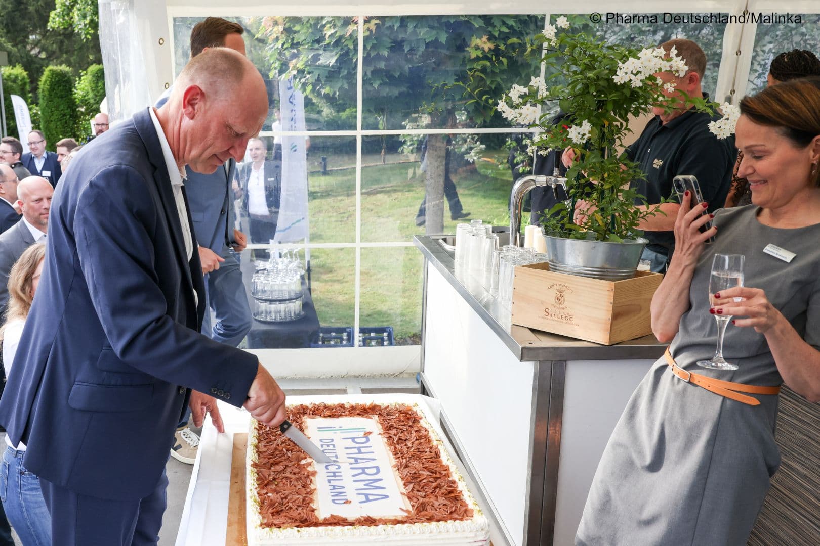 Hoch konzentriert: Jörg Wieczorek (Pharma Deutschland) darf die Torte anschneiden, Dorothee Brakmann hält den Augenblick per Foto fest.