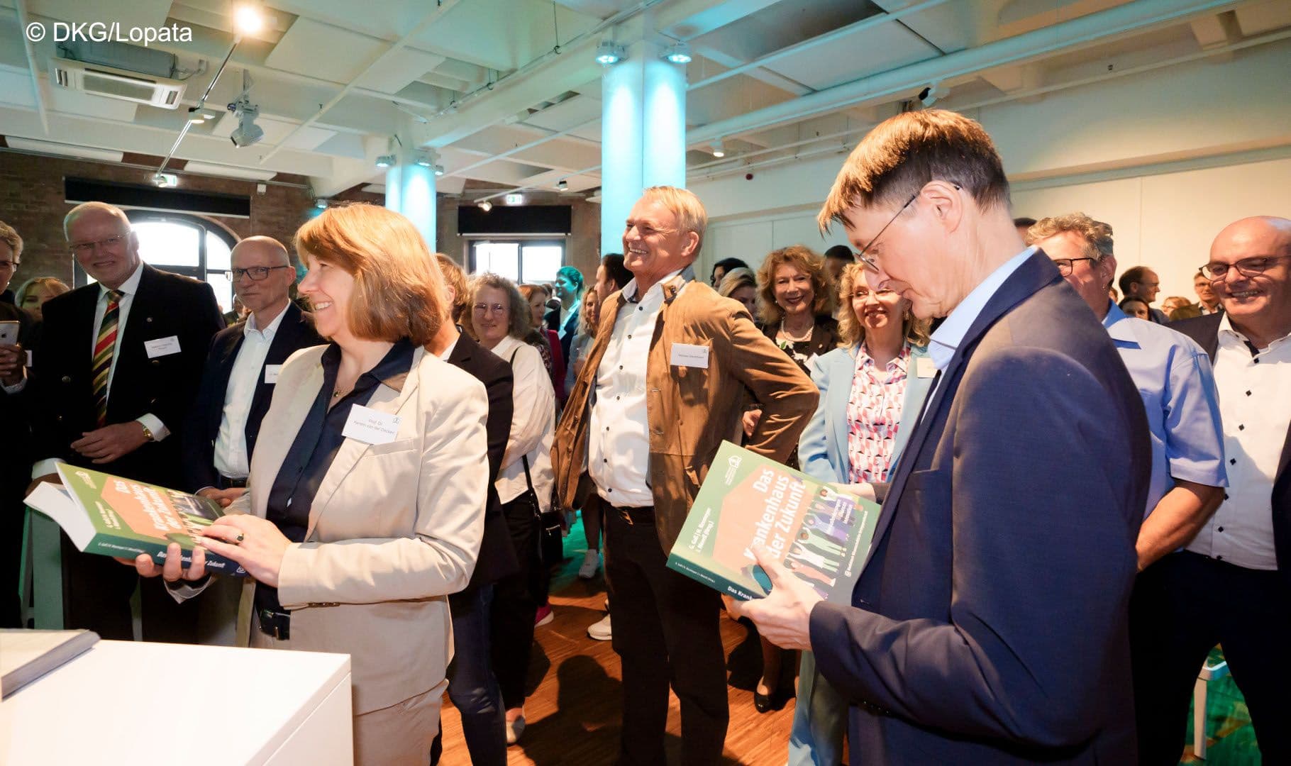 Der Bundesgesundheitsminister blickt interessiert auf das neue Krankenhausbuch.
